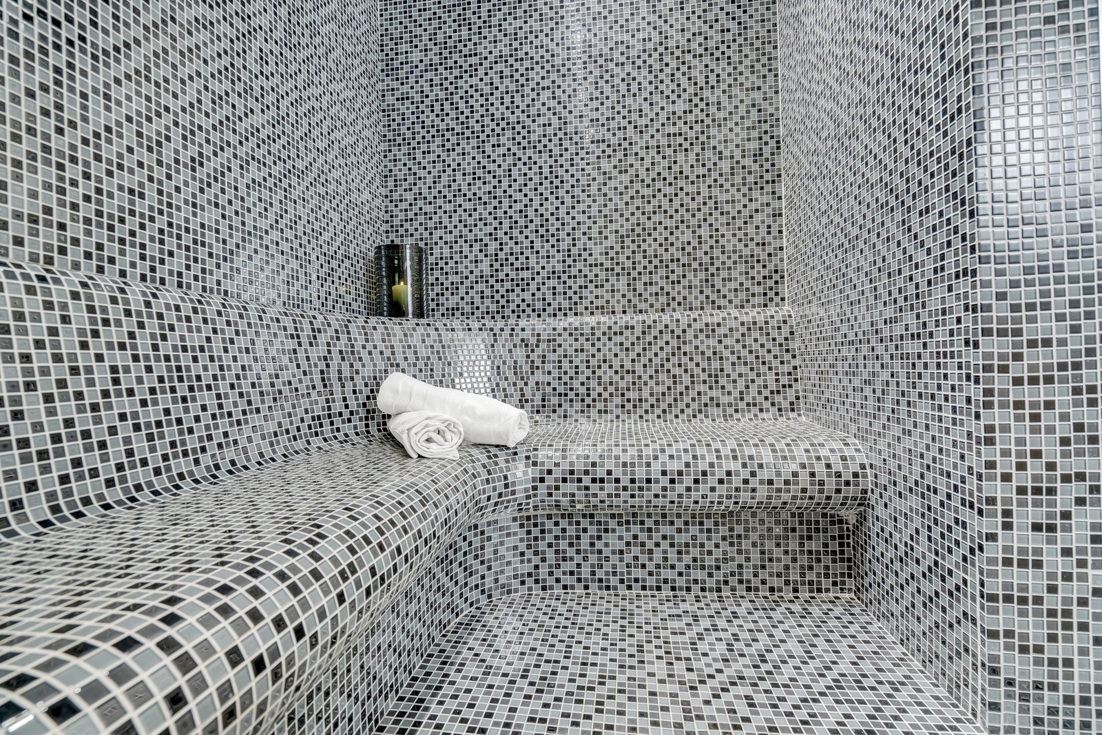 Tyrkisk dampbad med benker, gulv og vegger belagt med elegante mosaikkfliser - en eksklusiv oase for avslapning Galleribilde