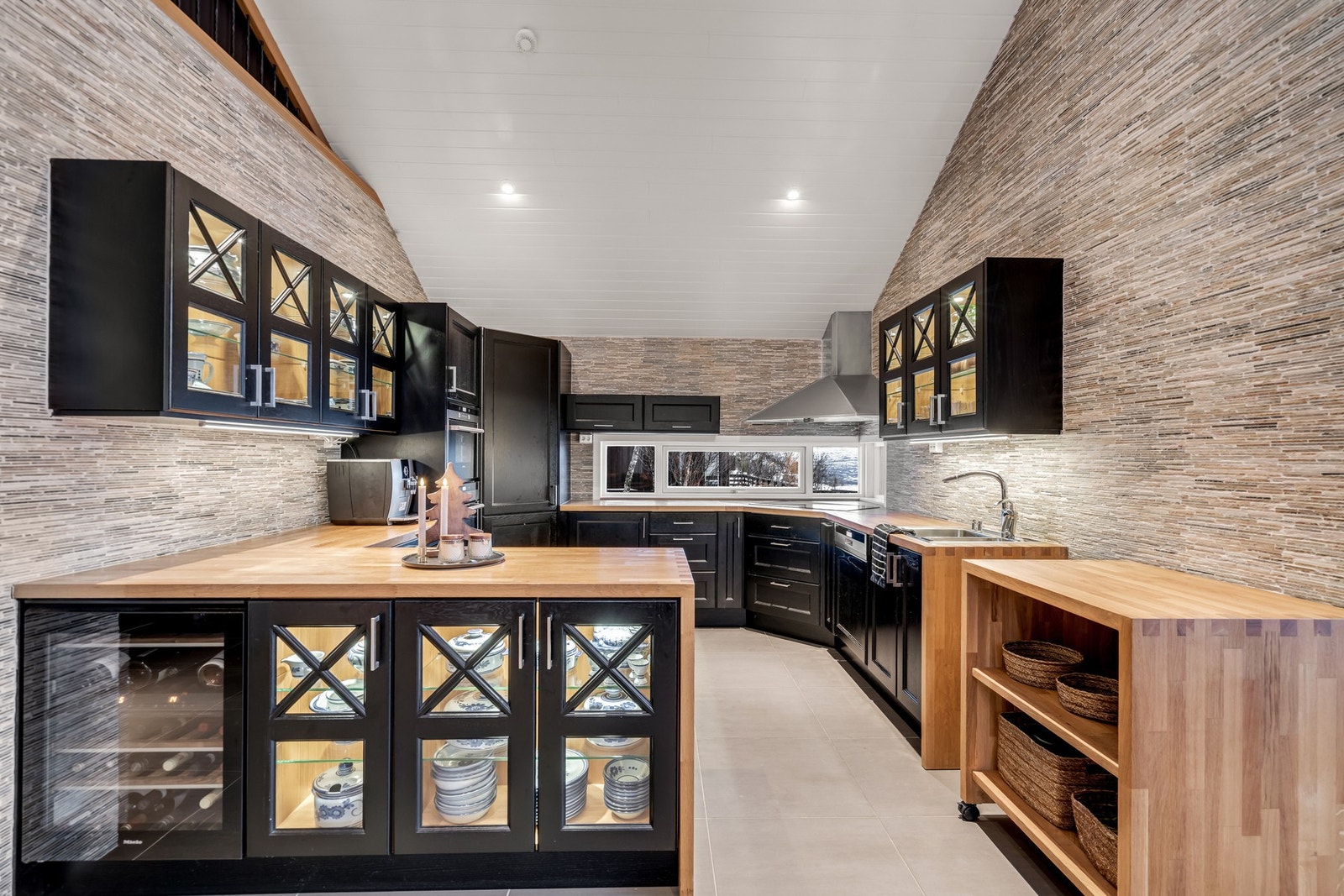 Påkostet kjøkken i stilren sort utførelse - komplett med integrerte hvitevarer som komfyr, steketopp, dampovn, kjøleskap, fryser og vinskap Galleribilde