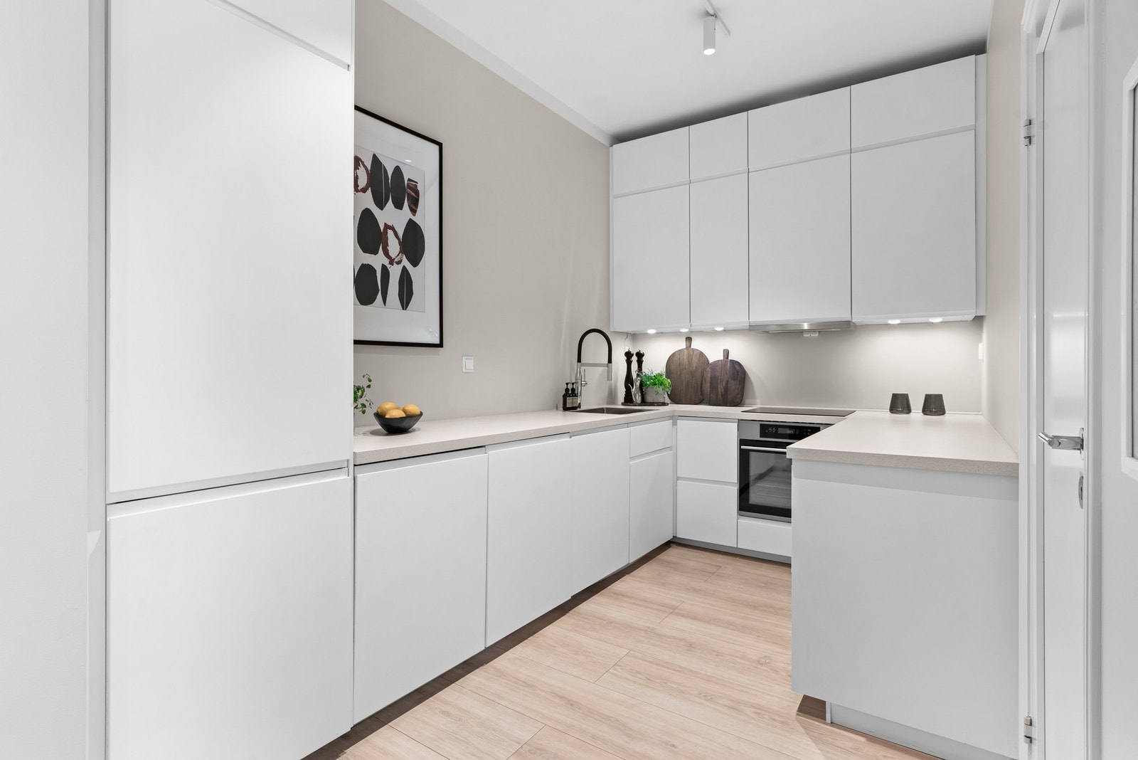 Kjøkkenet ligger i delvis åpen løsning mot stuen. Den delikate innredningen fra 2021 har rikelig med skap- og benkeplass. Galleribilde