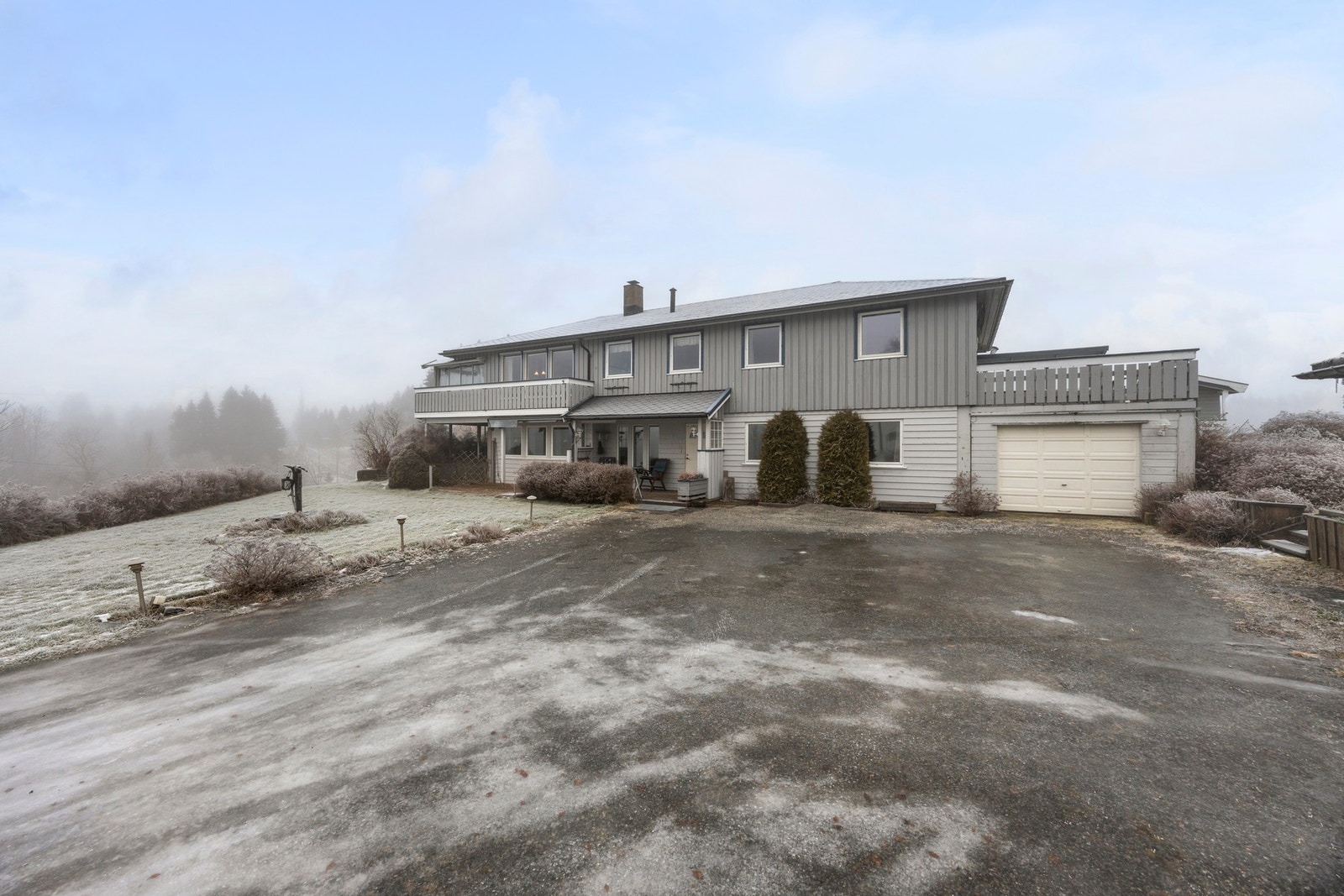 Pent opparbeidet tomt med asfaltert gårdsplass, belysning, busker og trær Galleribilde