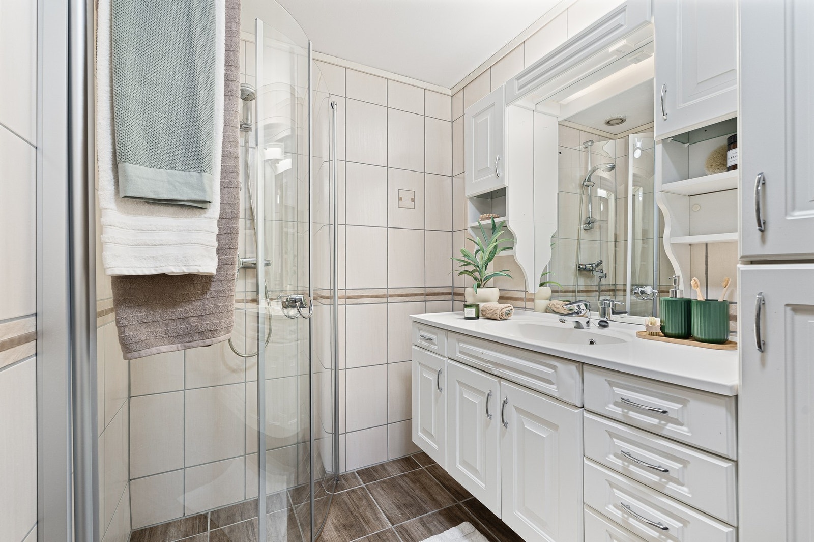 Badet er utstyrt med innfellbare dusjdører og servant i laminert utførelse. Galleribilde