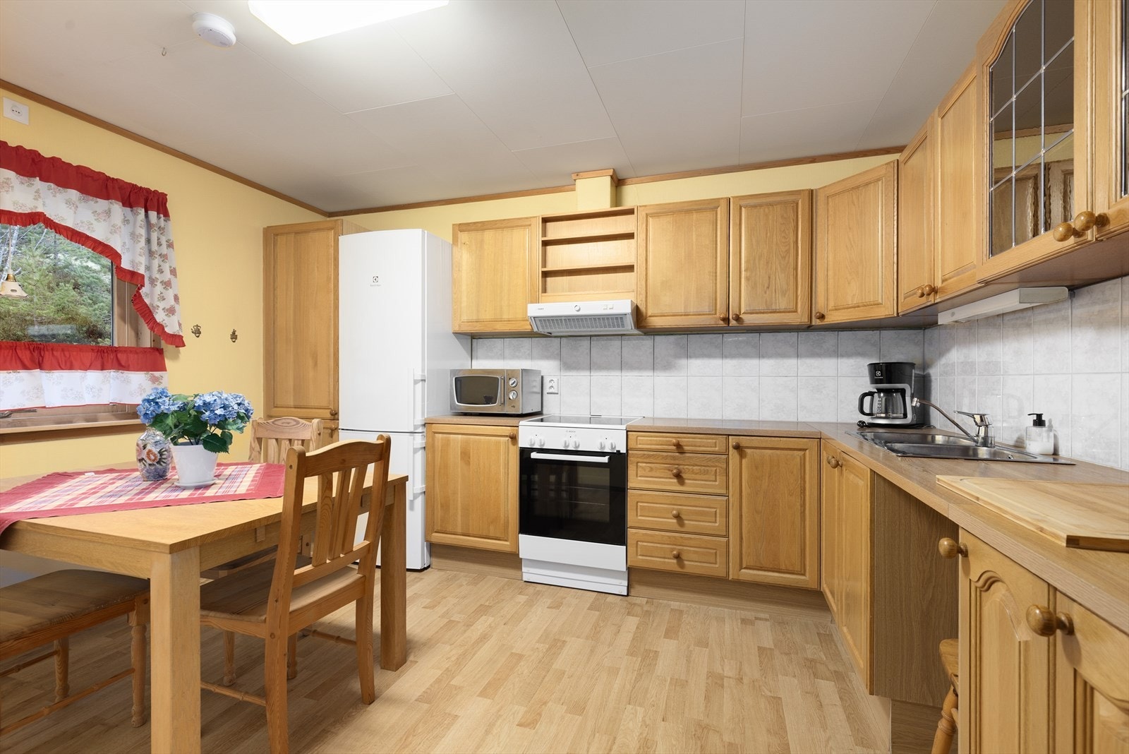 Kjøkkenet har innredning med profilerte fronter og laminert benkeplate med nedfelt oppvaskkum i stål. Det er avsatt plass til frittstående hvitevarer som komfyr og kjøleskap. Galleribilde