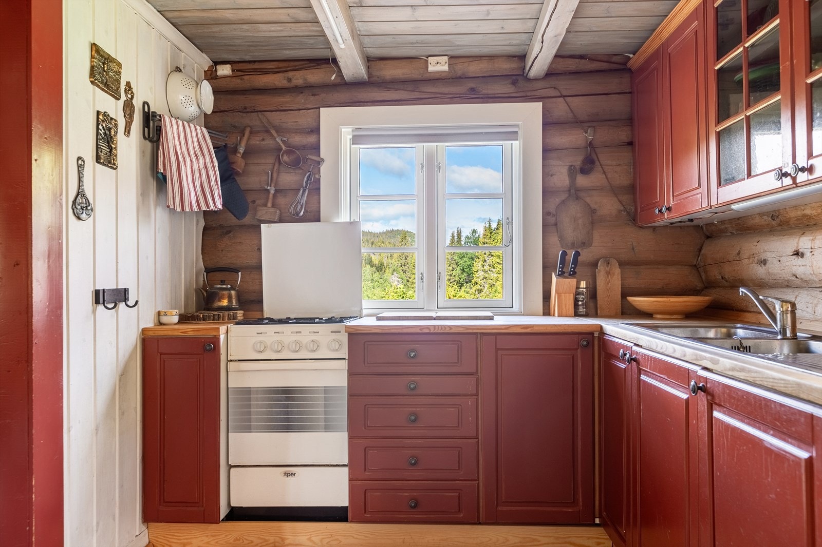 Innredningen har godt med benk- og skapplass, og består av profilerte fronter i heltre og heltre benkeplate med nedfelt oppvaskkum av stål. Komfyr og kjøleskap med propandrift. Galleribilde