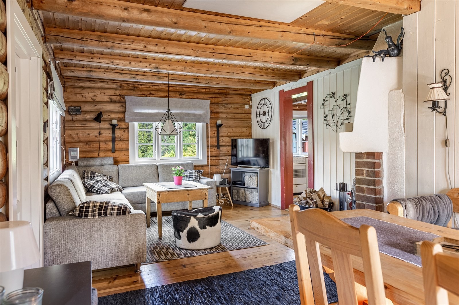 Inne i hytta er det koselig stue med yttervegger i tømmer og flat himling med tømmeråser, noe som gir et fint hyttepreg. Fotograf: Ingvild Sveen Joplassen. Galleribilde