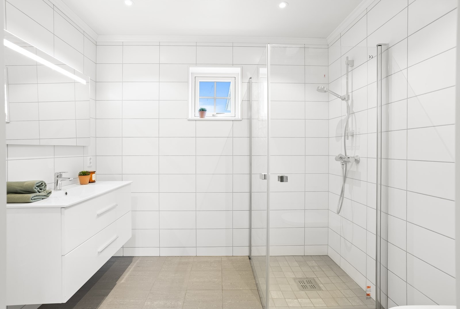 Moderne bad med flislagte overflater, dusjhjørne, baderomsinnredning med mye lagringsplass og vegghengt wc. Galleribilde