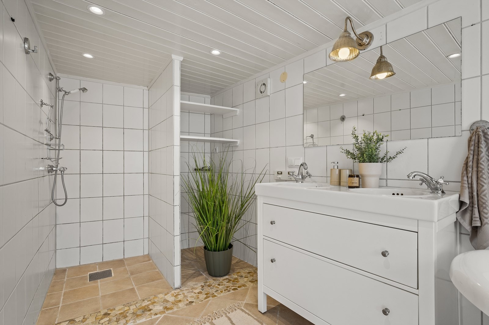 Badet er utsturt med dusjhjørne, badekart, toalett, og innredning med dobbel servant. Det er opplegg for vaskemaskin på badet Galleribilde