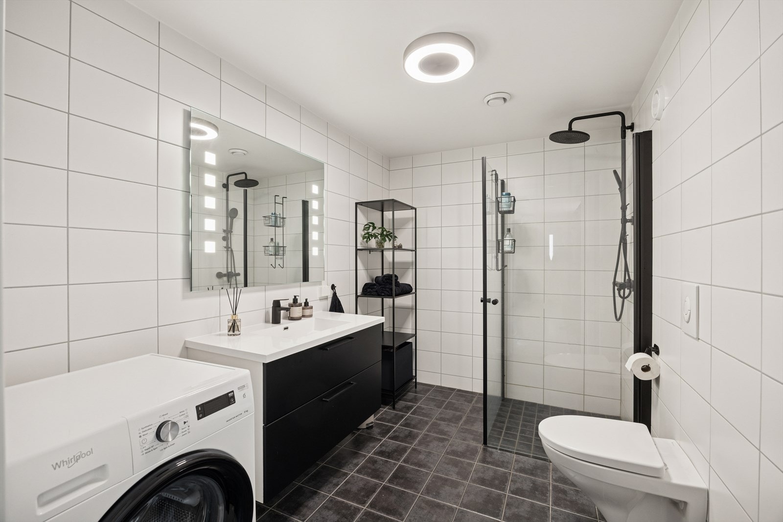 Boligens bad er flislagt med varmekabler i gulv. Det er tidløse fliser med sorte detaljer på innredningen. Galleribilde