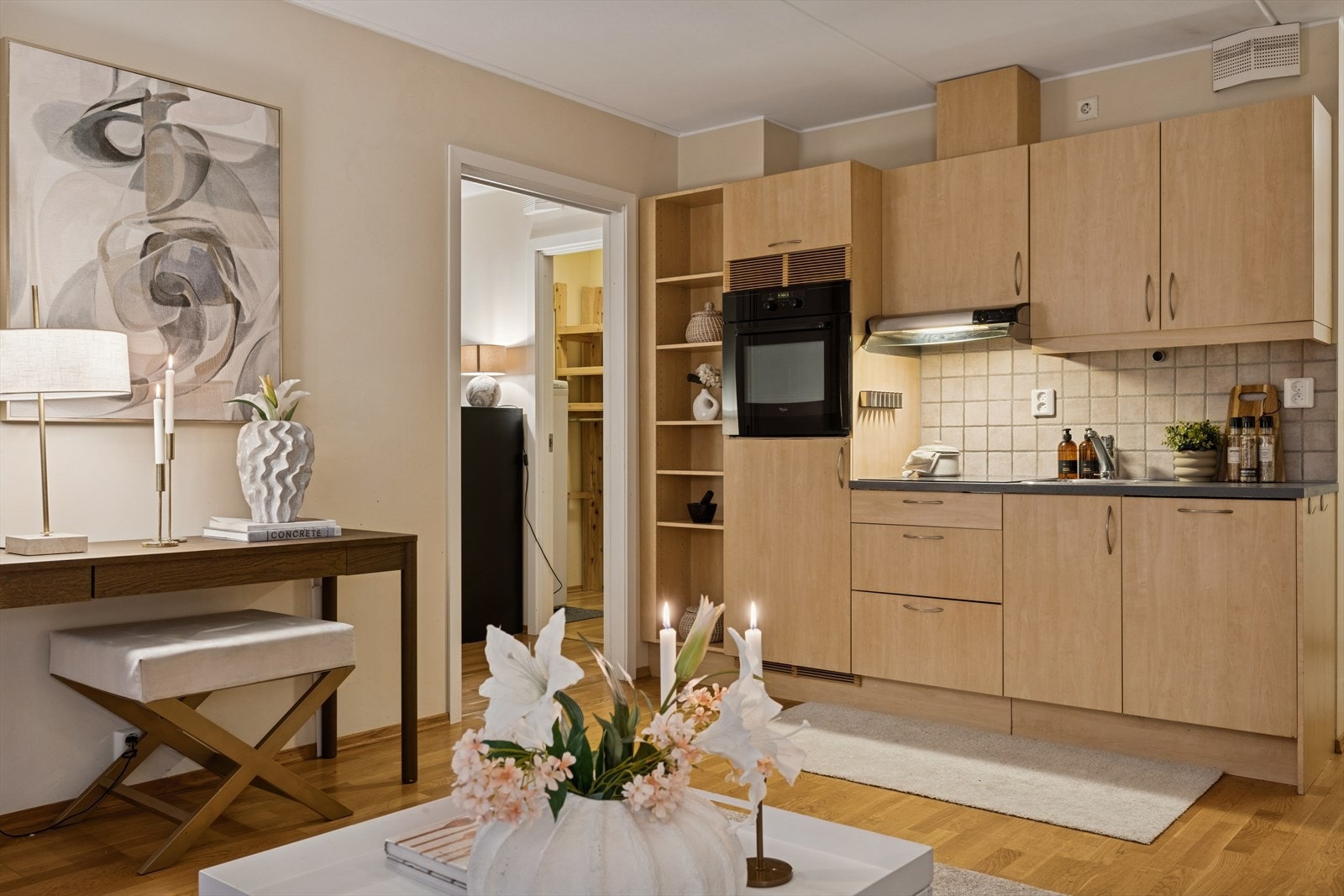 Stilren kjøkkeninnredning med folierte skrog med slette fronter, laminert benkeplate og flis på vegg over benkeplate som gir et gjennomført uttrykk. Mekanisk avtrekk over stekesone. Galleribilde