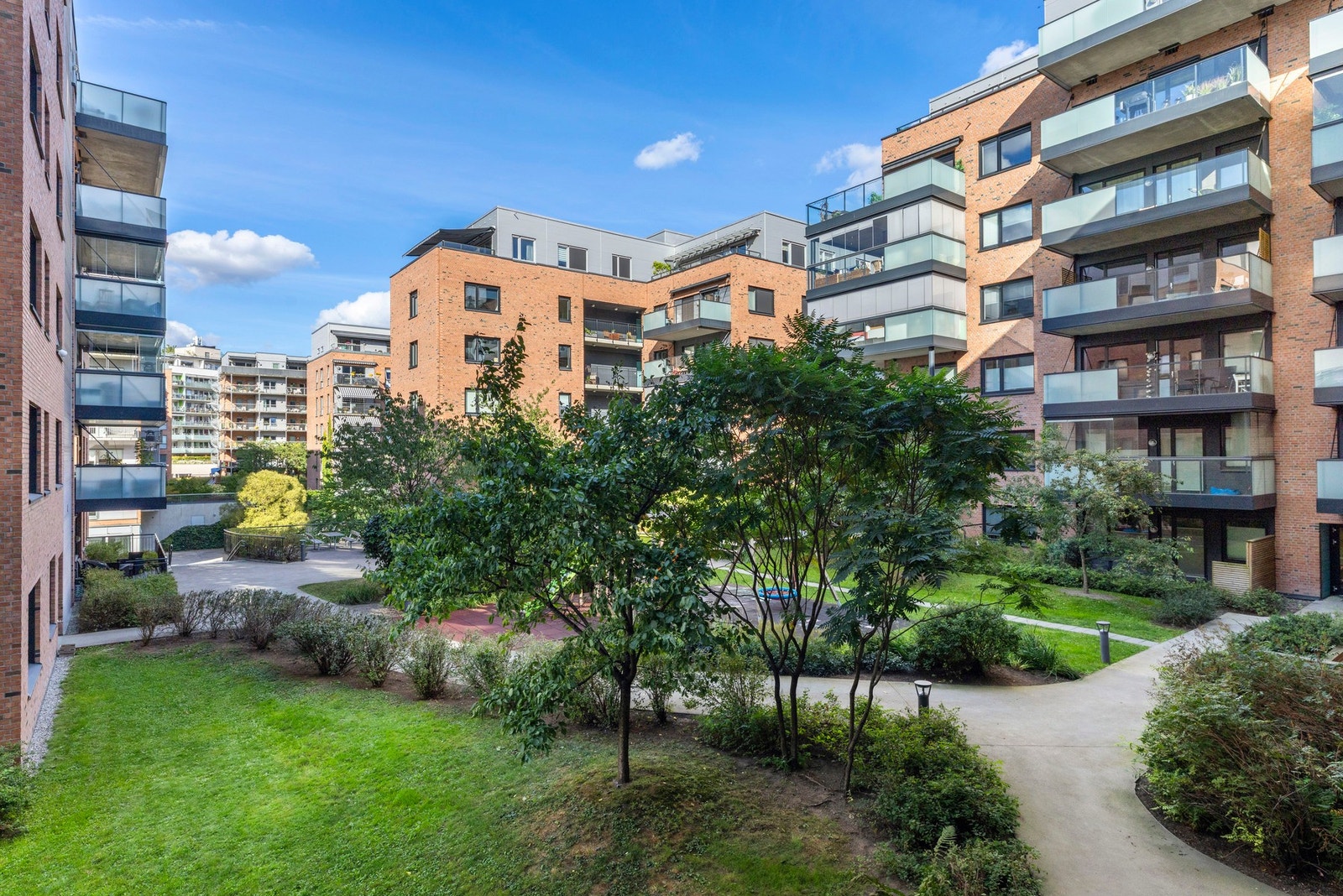 Et indre gårdstun er opparbeidet med gressplen, hellelagte stier, pergolaer og hyggelige sittegrupper Galleribilde