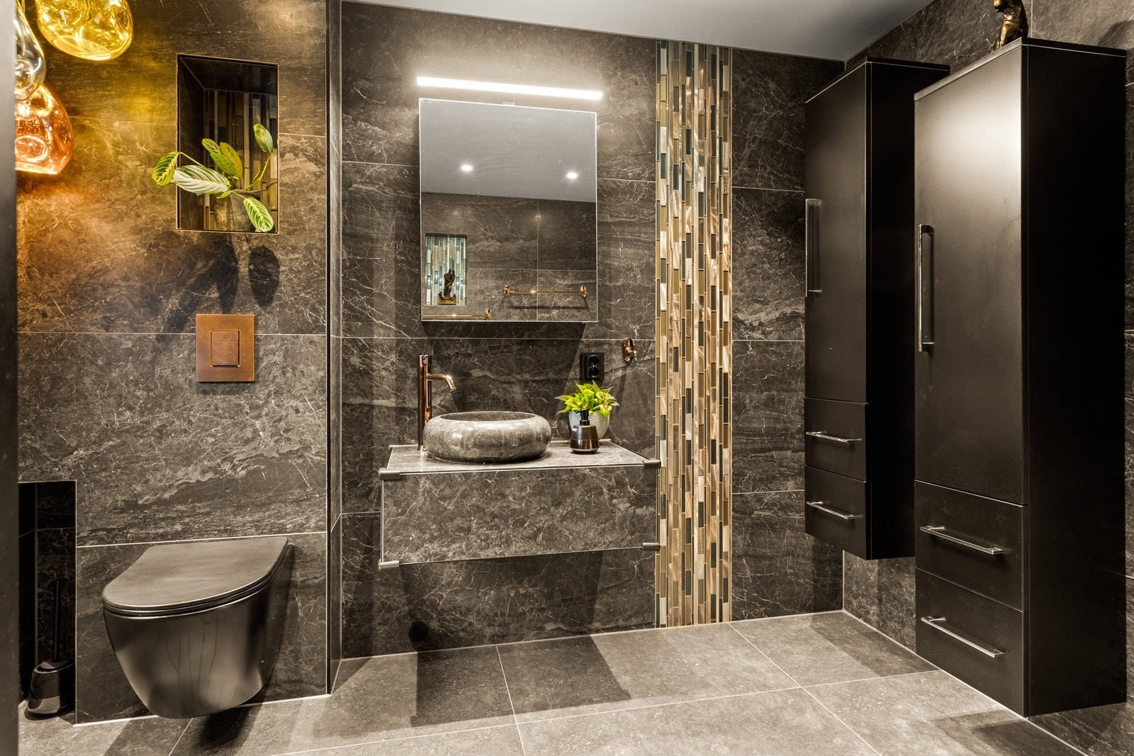 Benk med oval servant i stein og overhengende speilskap gir praktisk oppbevaring. Dusjen har kombinasjon av bred hodedusj og håndholdt armatur. Galleribilde