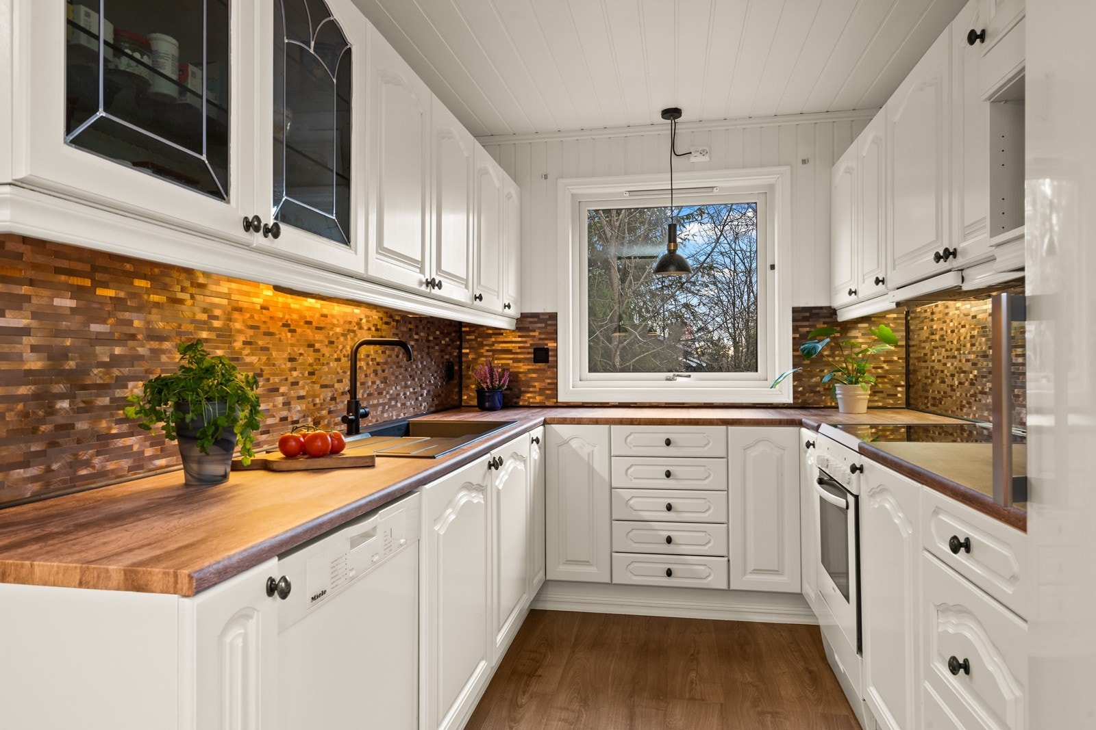 Profilerte, malte fronter og folierte benkeplater gir kjøkkenet en klassisk stil. Galleribilde