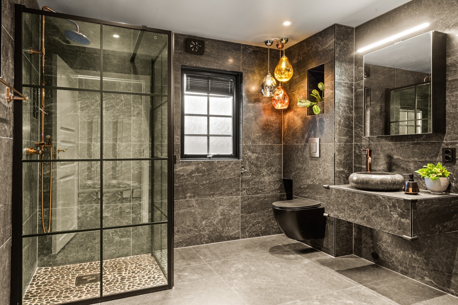 Flislagte overflater og elektriske varmekabler gir robust våtromsløsning. Badet ventileres via elektrisk vifte i veggen. (Pendellamper følger ikke salget.) Galleribilde