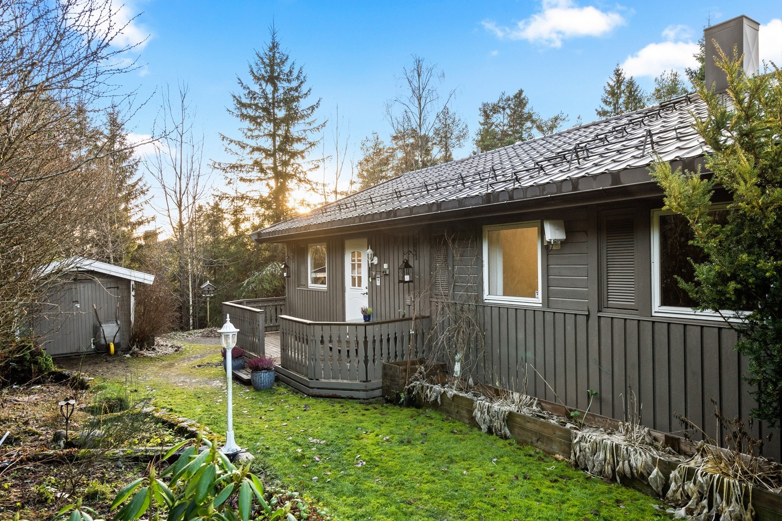 Boligen har en skrånende tomt med plenareal og beplantning rundt. Galleribilde