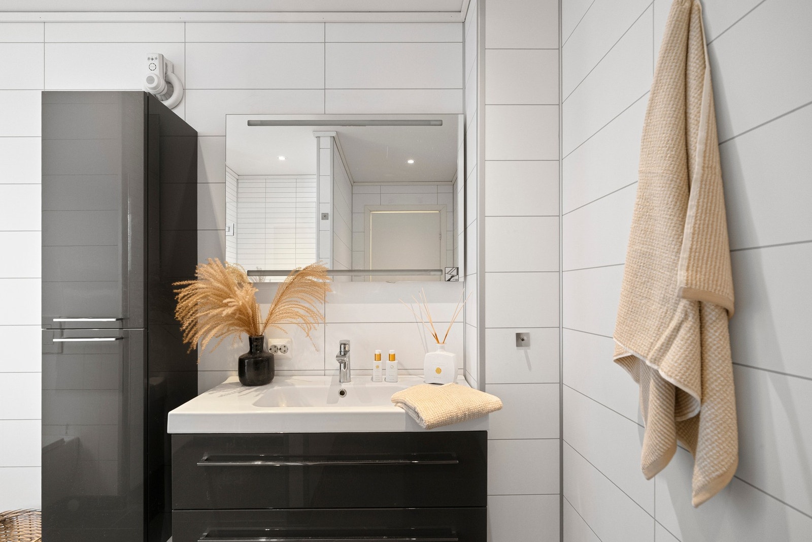 Badet er innredet med nedfelt servant i baderomsinnredning, veggmontert toalett, dusjhjørne med glassvegger og opplegg for vaskemaskin. Galleribilde