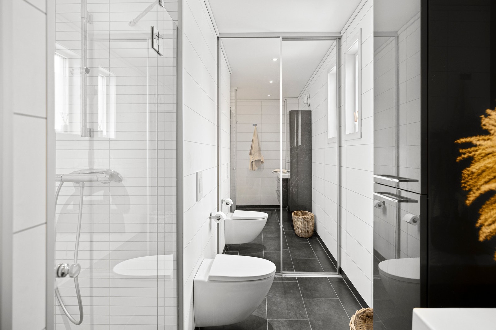 Badet fremstår som moderne og stilrent, med vegger kledd i baderomsplater og malt tak. Galleribilde