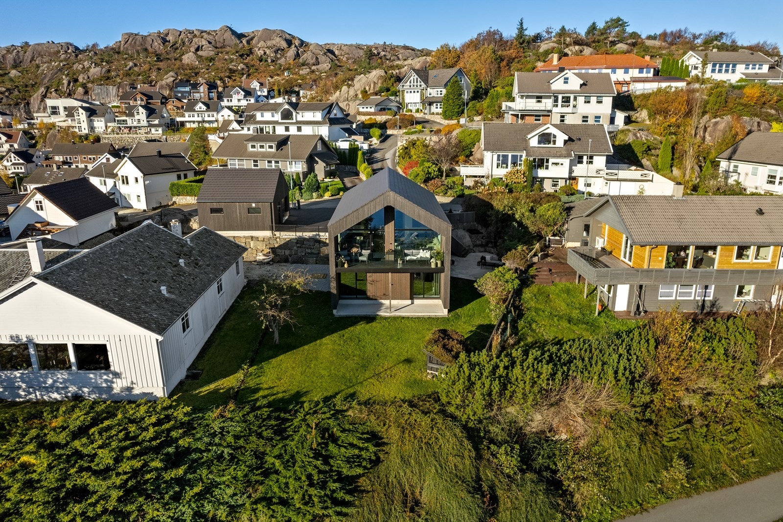 Tomten er lettstelt og opparbeidet med plen, beplantning, terrasse, fine murer og et asfaltert gårdsrom. Galleribilde