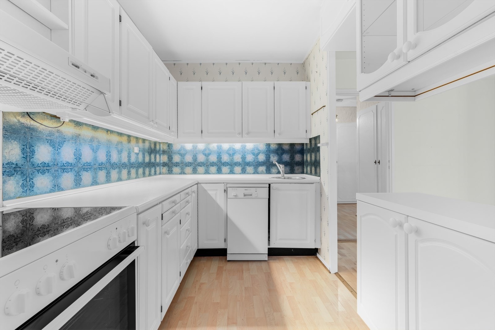 Kjøkkenet har en innredning med profilerte fronter, enkelte overskap med glassfronter og en benkeplate i laminat. Galleribilde