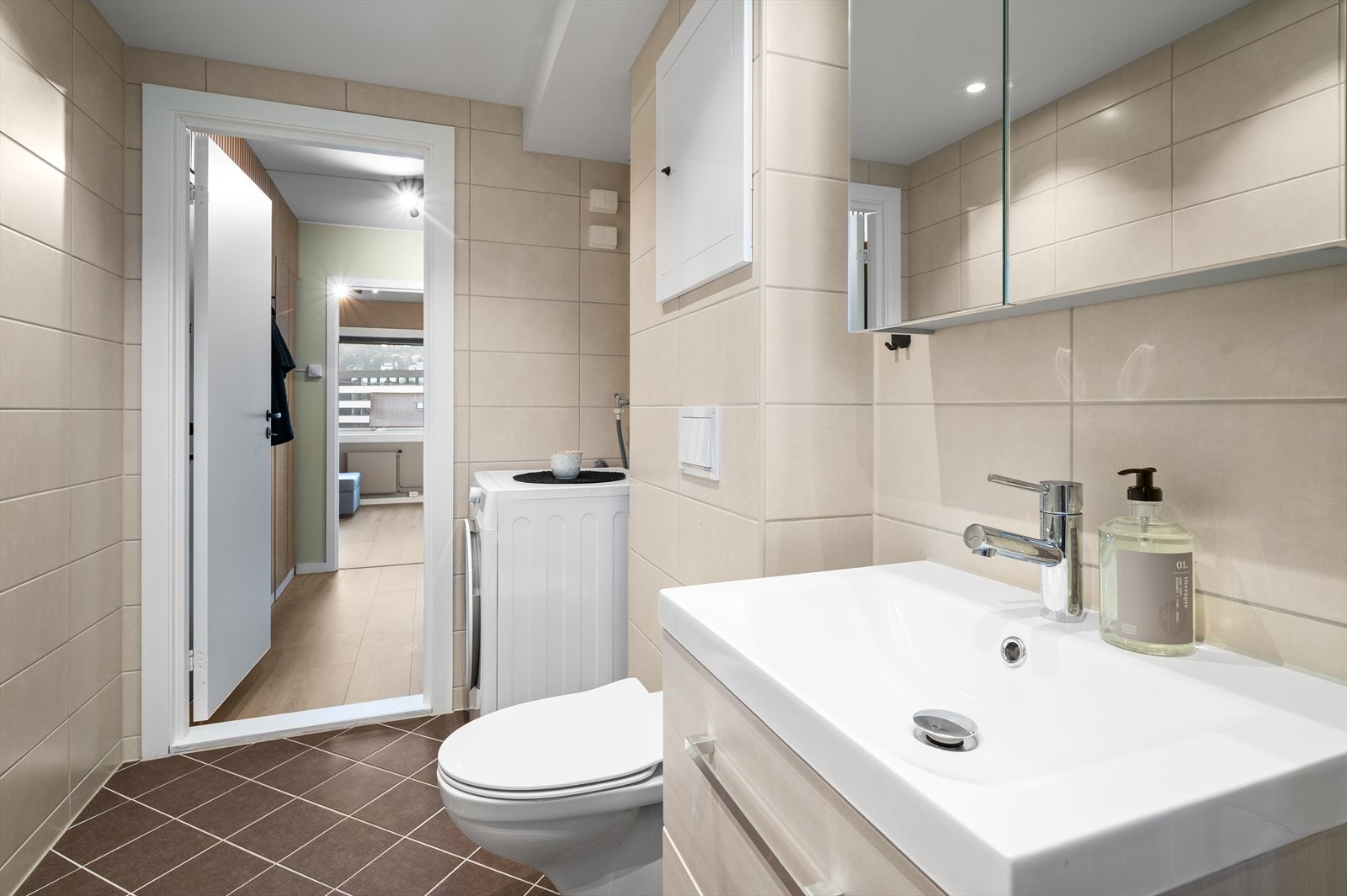 Lekkert bad med tidløse fliser, god plass og praktisk opplegg for vaskemaskin Galleribilde
