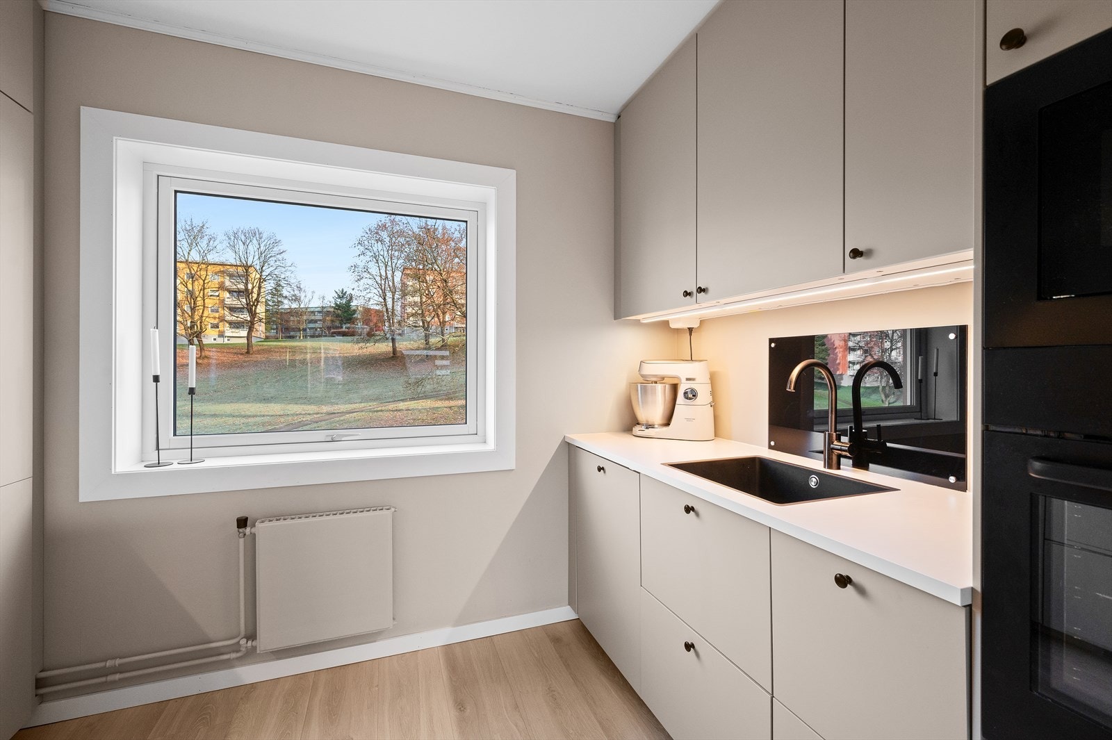 Kjøkkeninnredning med glatte fronter, laminert benkeplate med integrert kjøkkenkum og malt
vegg over kjøkkenbenk. Galleribilde