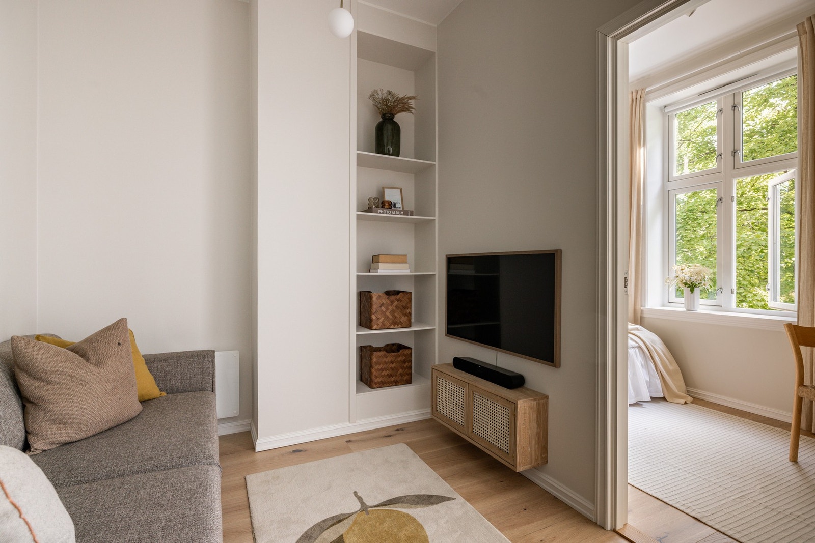 TV-stuen har rom for både sofa og tv-møblement. Her er det også bygget inn et praktisk og dekorativt hyllesystem for oppbevaring og utstilling. Galleribilde