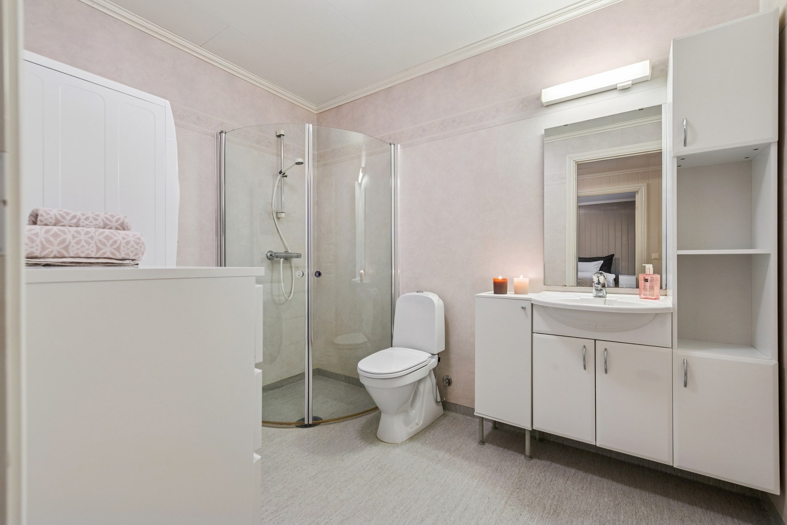 Funksjonelt bad med servant i innredning og dusjhjørne med glassdører. Galleribilde