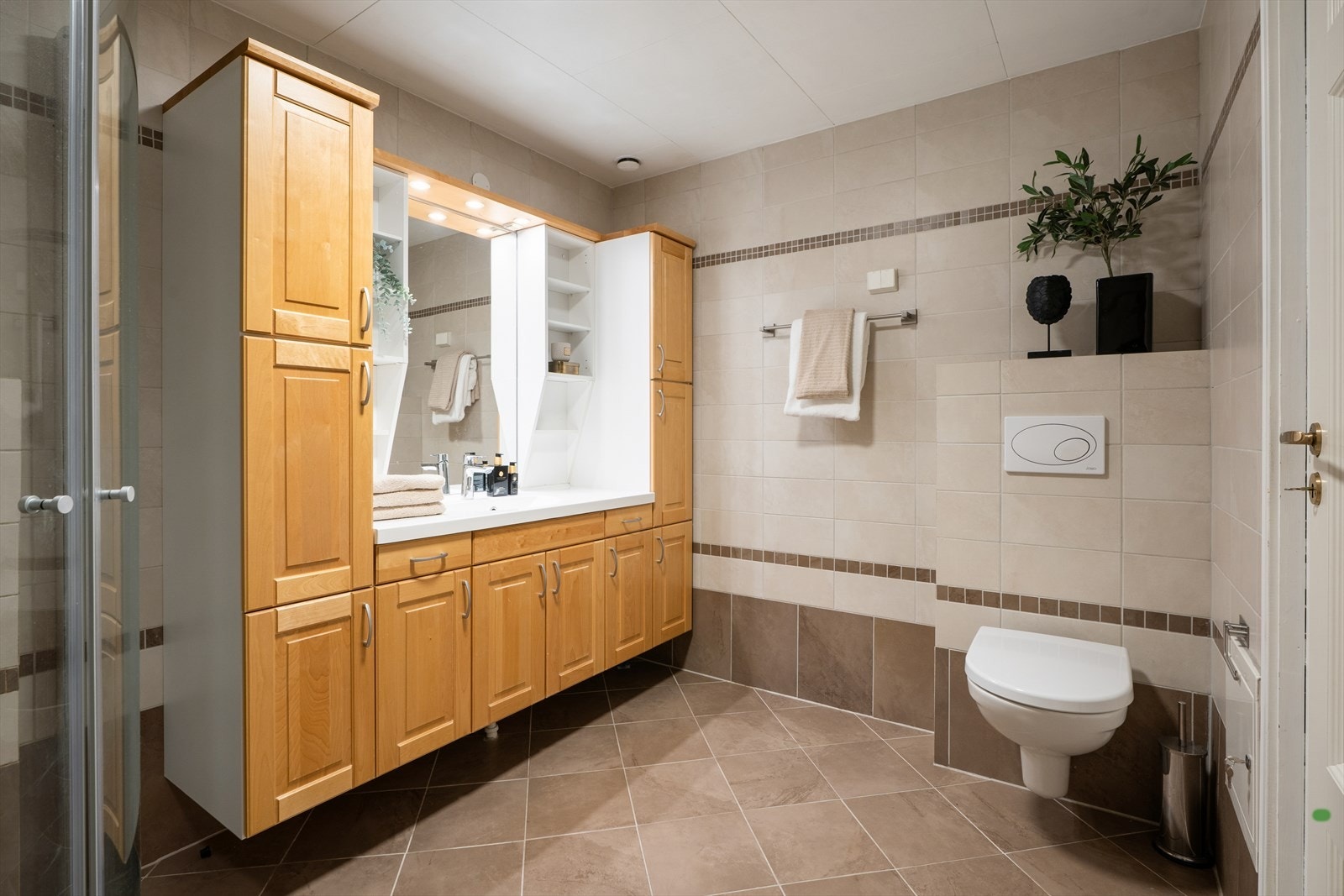 Badet fungerer som både baderom og vaskerom og er praktisk innredet med flislagte vegger og gulv. Galleribilde