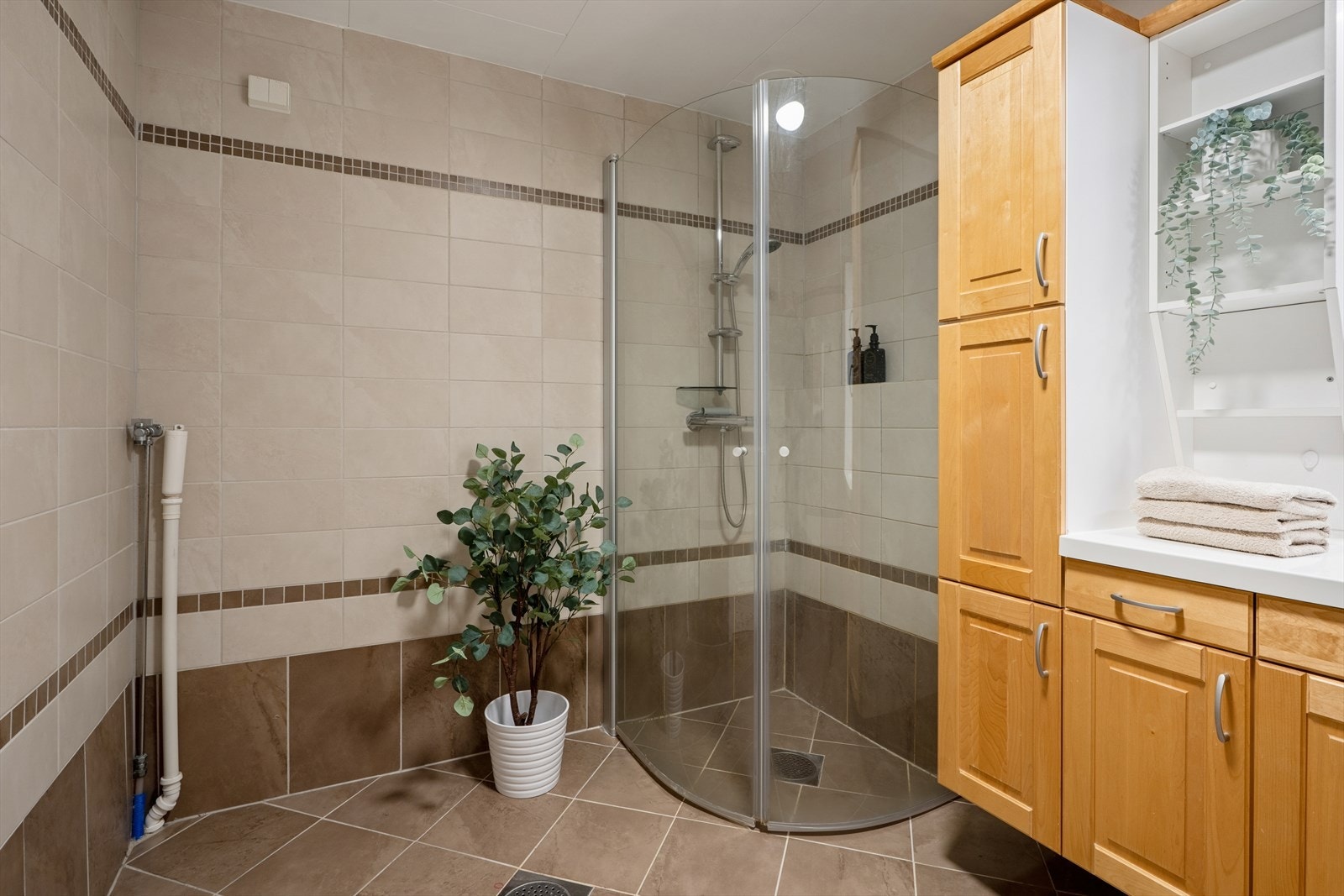 Rommet er utstyrt med veggmontert toalett, dusjhjørne med glassvegger, servant med innredning og opplegg for vaskemaskin. Galleribilde