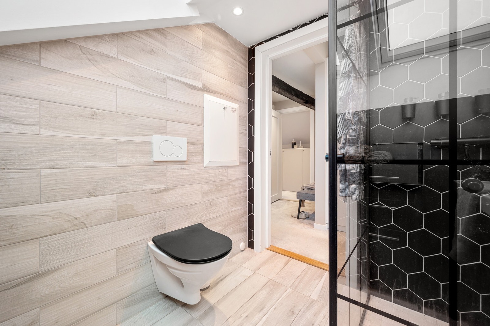 Baderommet inneholder dusjhjørne, veggmontert toalett, kran og avløp for vaskemaskin, rørskap, servant med underskap og speil. Galleribilde