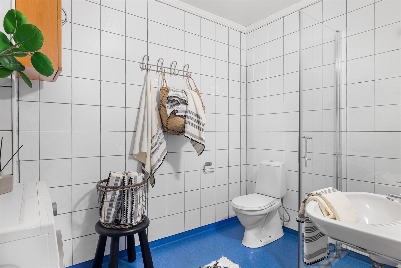 Badet er utstyrt med gulvmontert toalett, veggmontert servant og opplegg for vaskemaskin. Galleribilde