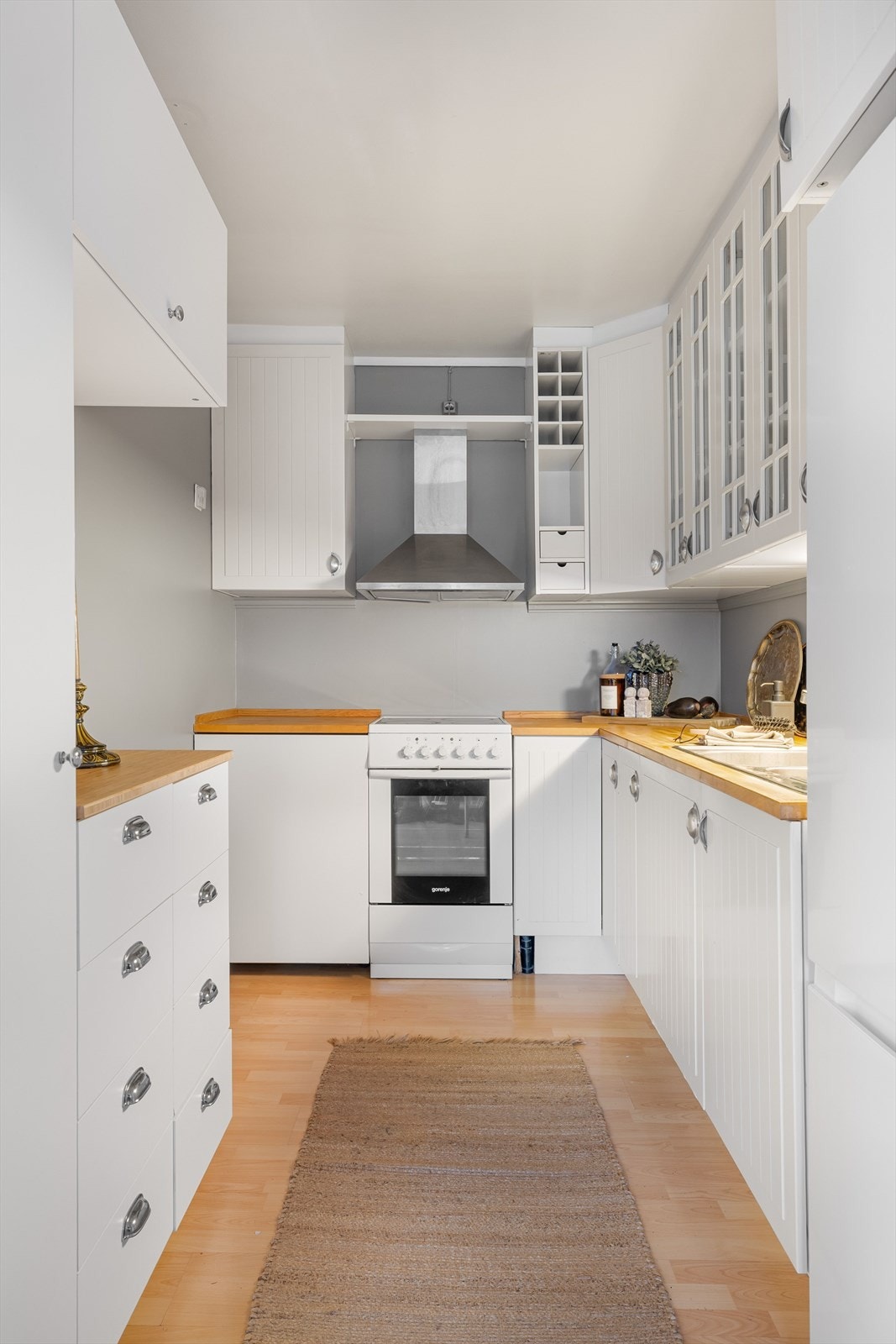 Lys innredning med plass for frittstående komfyr, kjøleskap og oppvaskmaskin. Galleribilde