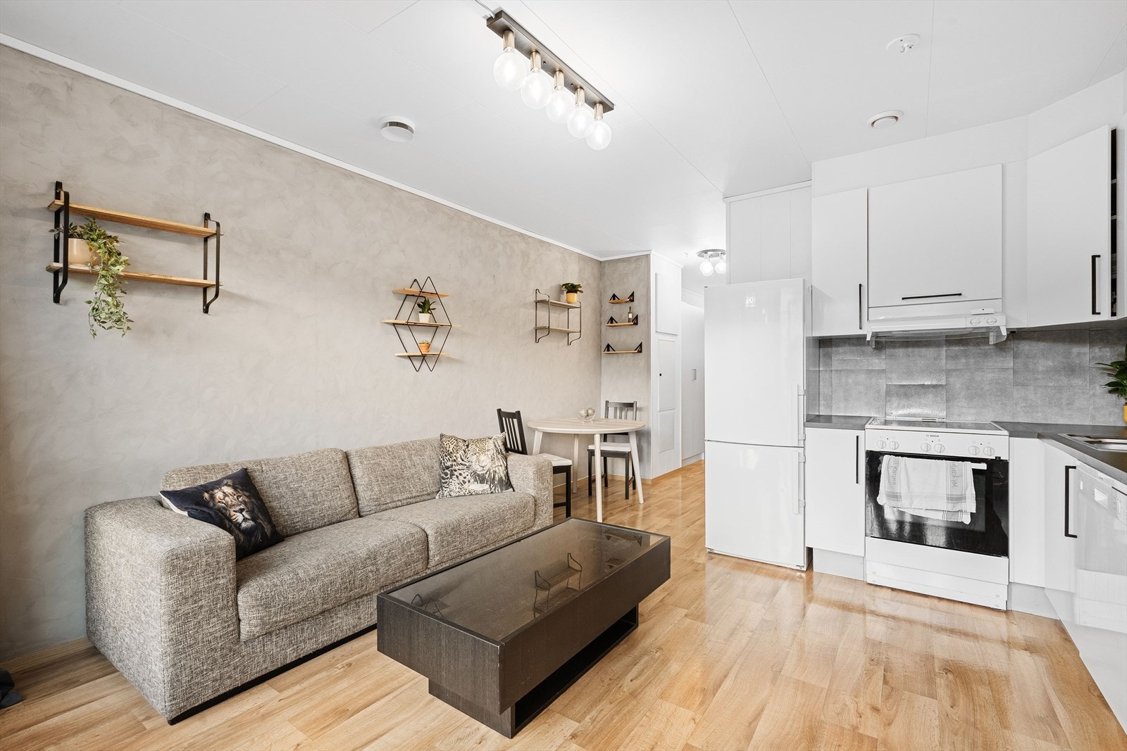 Leilighetens sosiale sone består av en åpen stue - og kjøkkenløsning Galleribilde