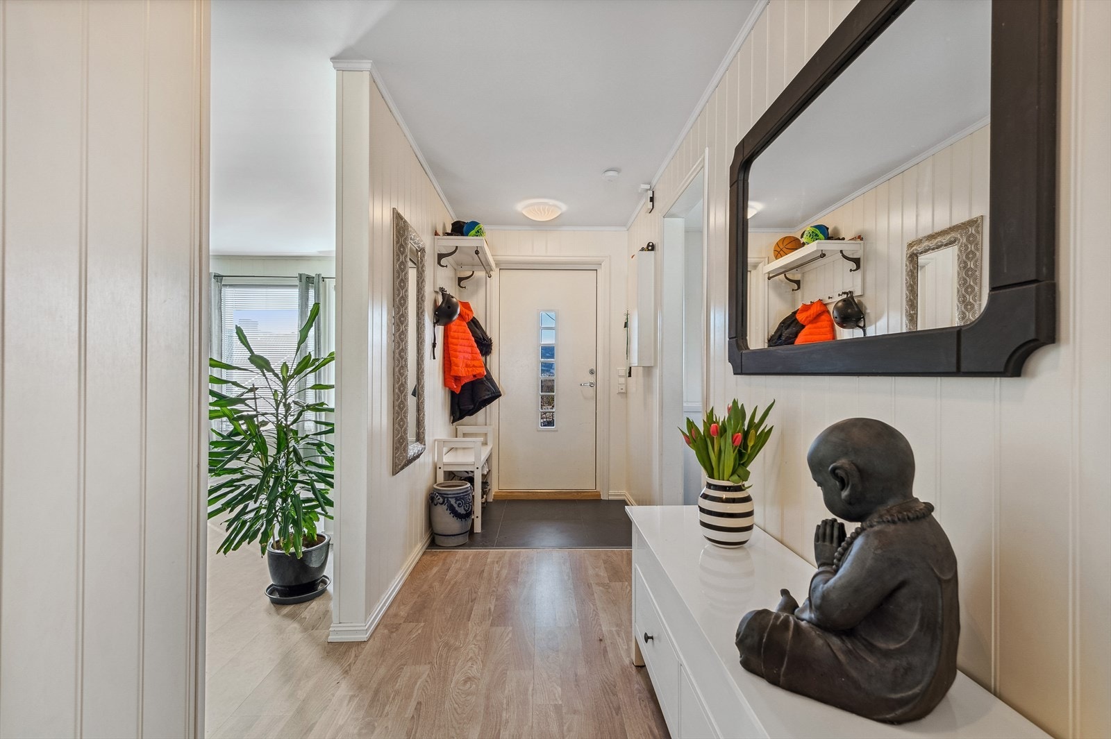 Ytterdøren har en lys overflate med rutet glassfelt, og entreen er utført med glatte malte vegger og lys himling. Gulvet er flislagt med varmekabler. Det er fin plass til oppbevaring av sko og yttertøy. Galleribilde