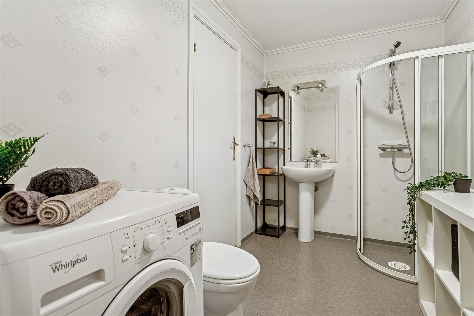 Baderom utstyrt med varme i gulv, dusj, opplegg for vaskemaskin, toalett, servant og speil. Galleribilde