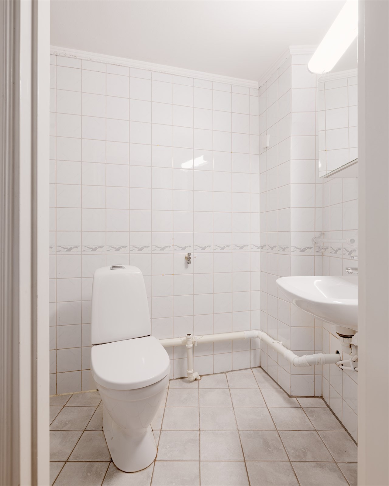 Lyst bad med flislagte overflater. Opplegg for vaskemaskin. Galleribilde