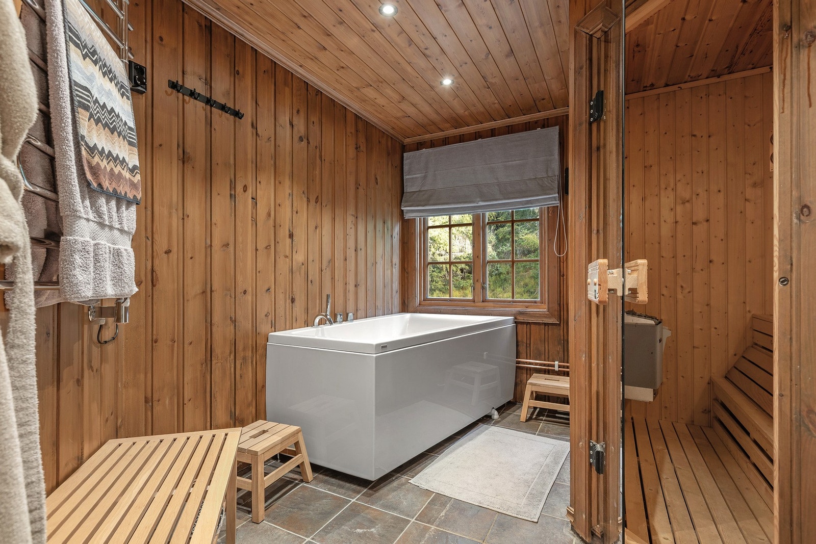 Fra ett av badene er det glassdør inn til badstue med benker og elektrisk badstueovn.