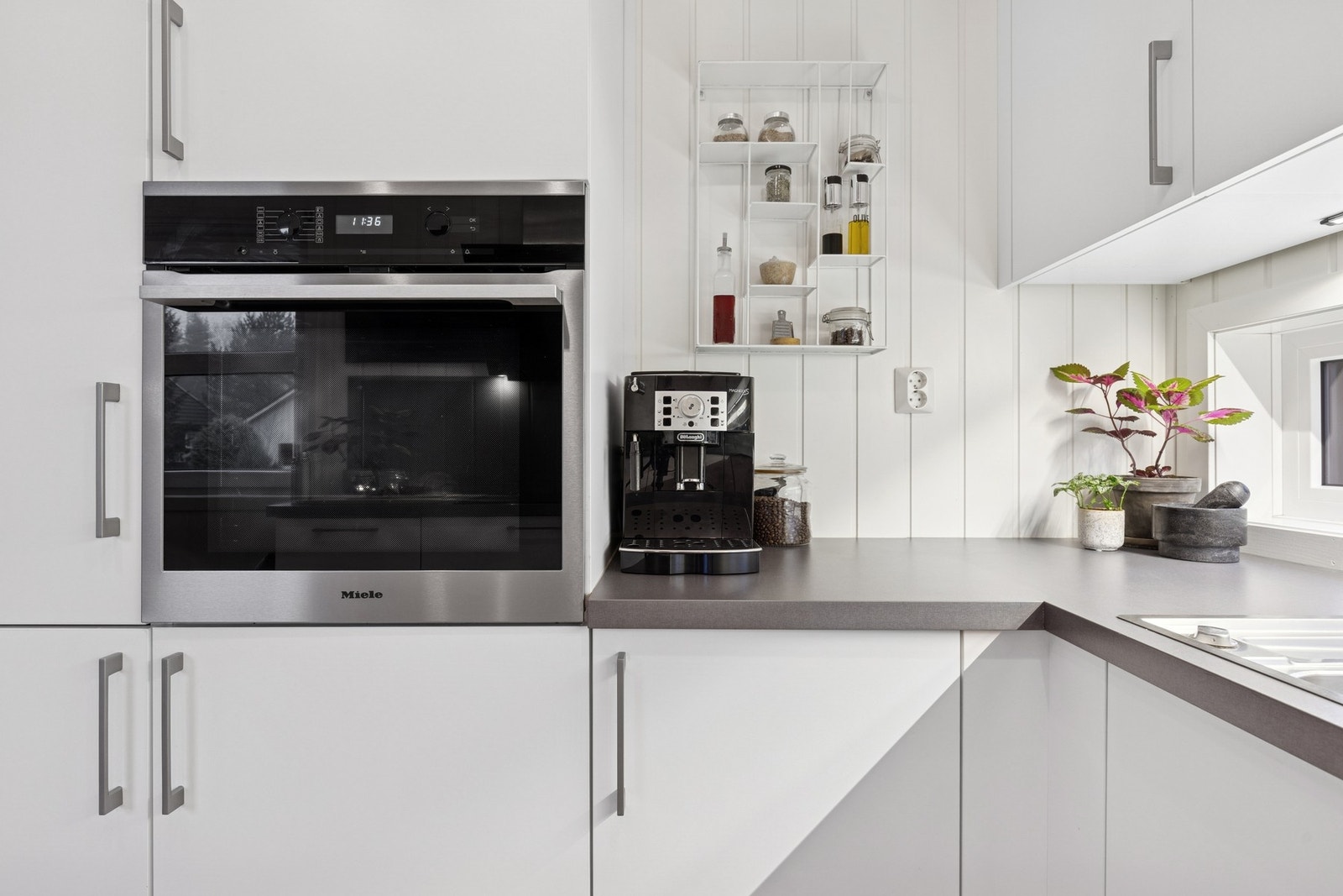 Kjøkkeninnredning med hvite fronter i glatt utførelse, laminat
benkeplate. Galleribilde