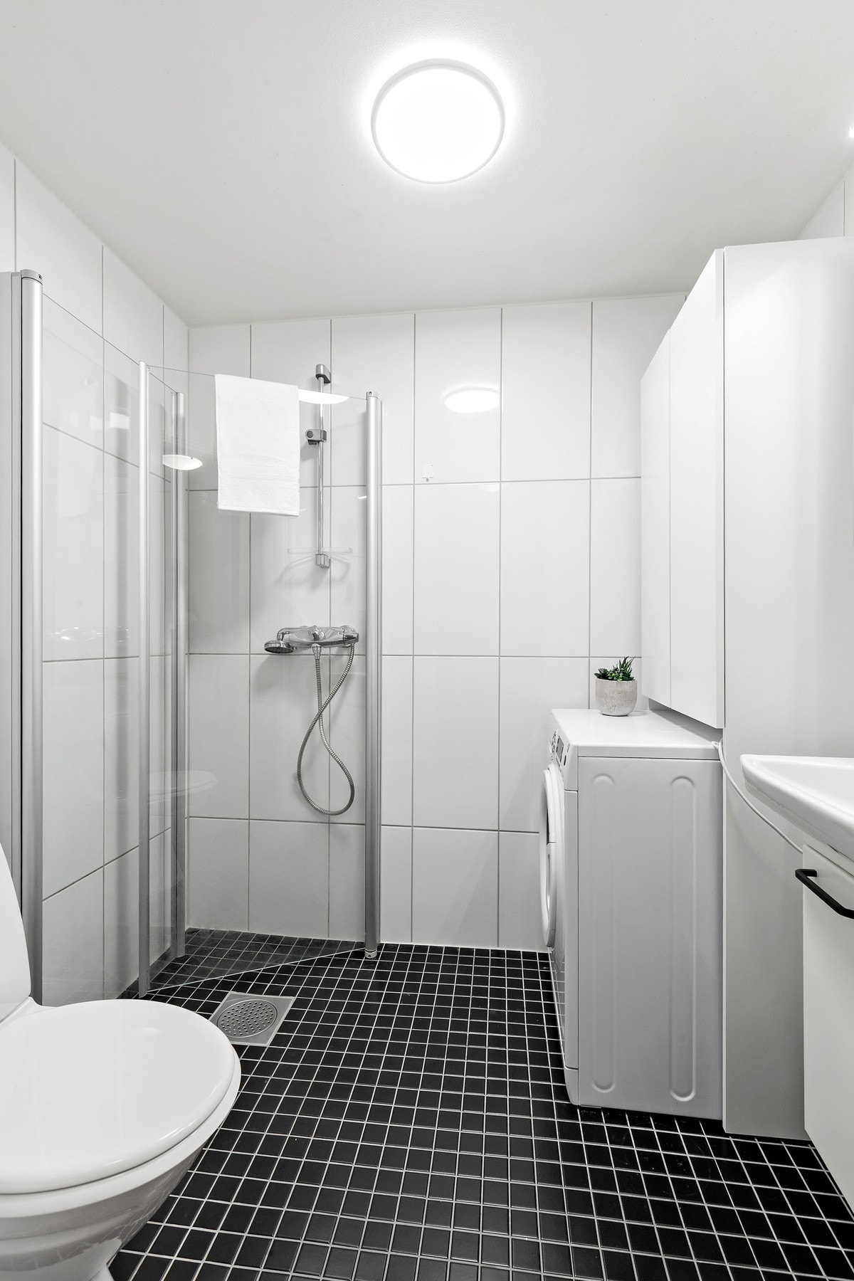 Flislagt baderom på 3 kvm. Her får du wc, dusjhjørne med innfellbare dører, opplegg for vaskemaskin samt gode servant- og speilskap. Galleribilde