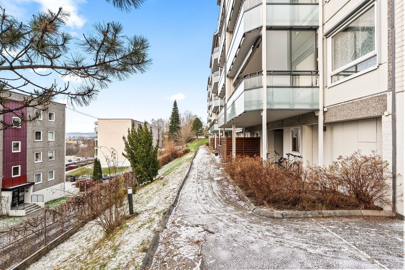 Leiligheten ligger i blokkens underetasje, en trapp ned fra inngangspartiet. Det er også mulig å gå rett inn på leilighetsplanet fra andre siden av blokken (avbildet). Galleribilde