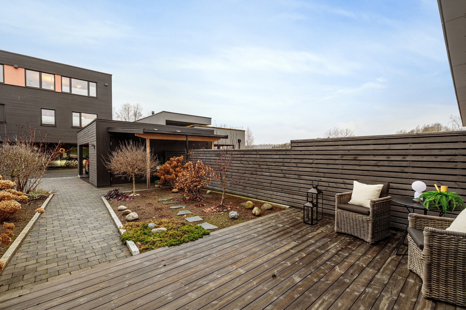 Steinbelagt oppkjørsel med et opparbeidet hagearel i forkant av boligen. Galleribilde