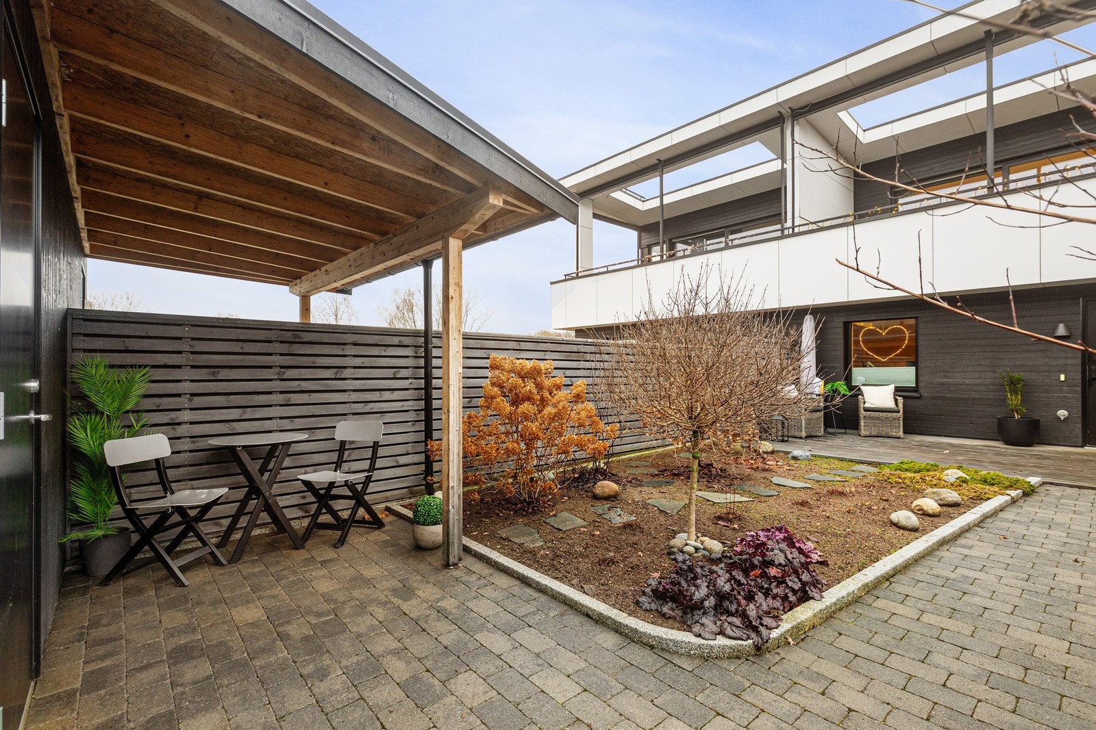 Inngangspartiet er privat med skjermvegg mot naboene på begge sider. Morgensol i krok ved carporten. Galleribilde