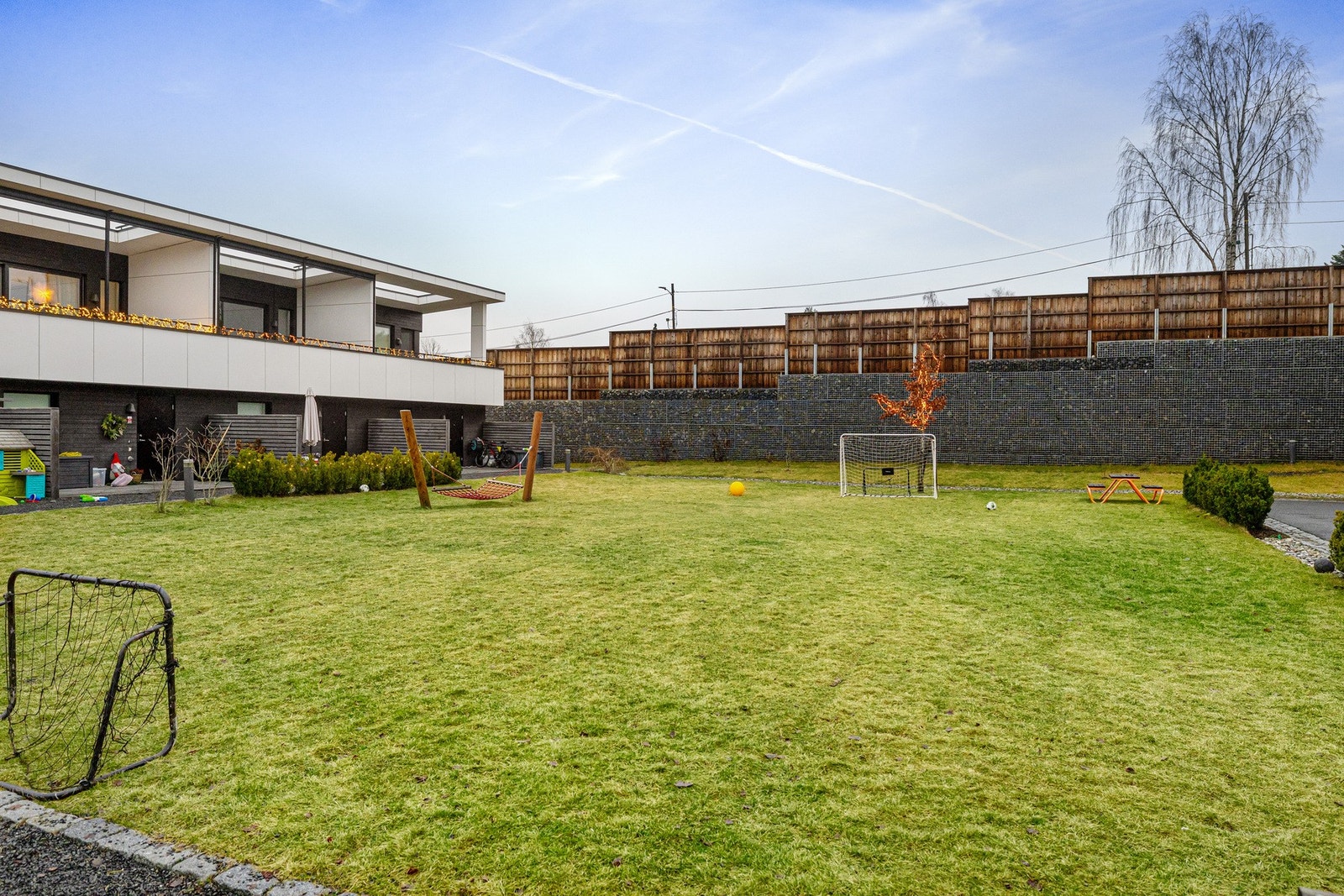 Store grøntarealer utenfor rekkehusene hvor barna kan løpe fritt rundt husveggene. Her leker barn i alle aldre sammen - de spiller fotball, turner og leker boksen går. Galleribilde