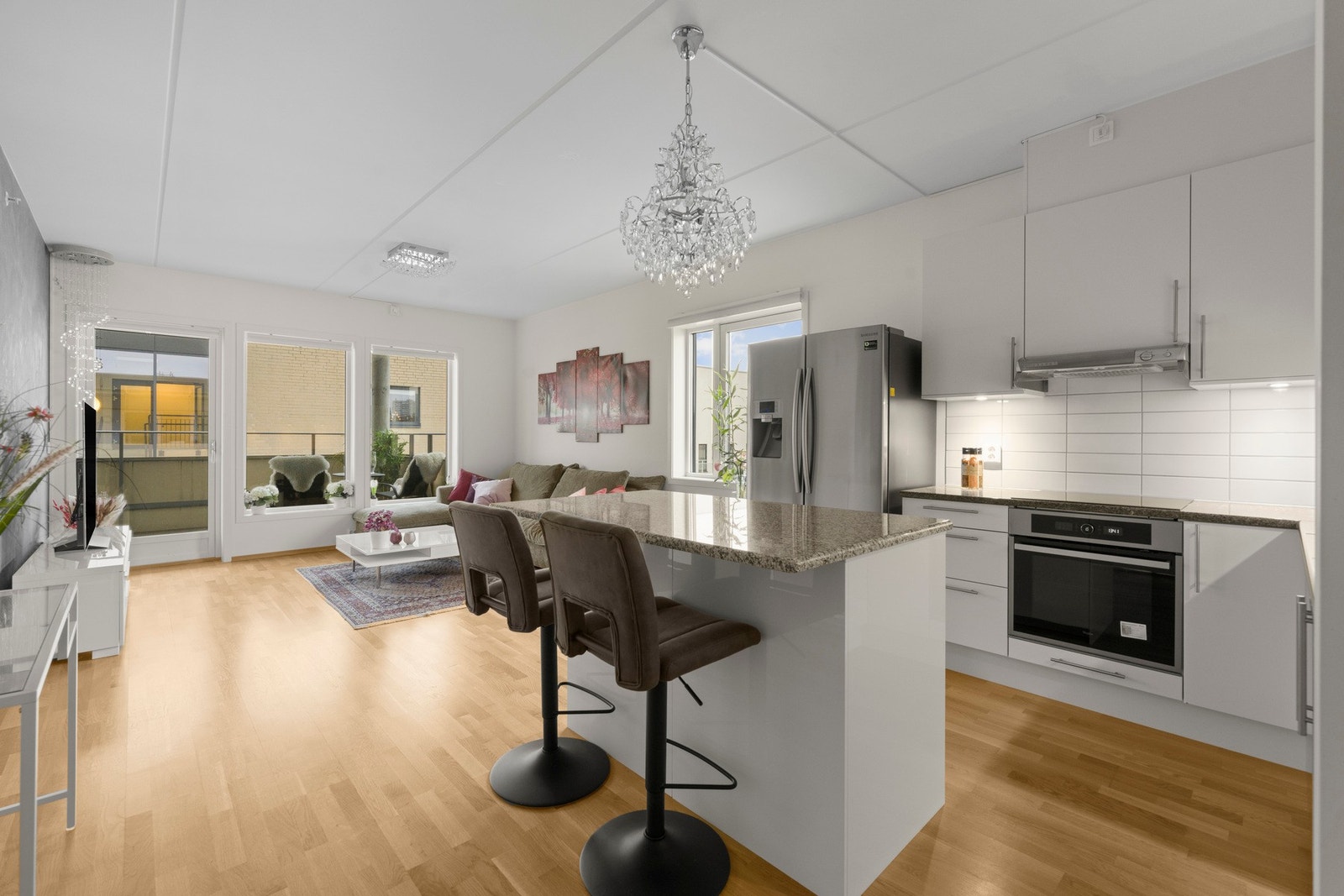 Kjøkkenøya fungerer som en naturlig overgang mot stuen og har sitteplass for to, perfekt til frokost, uformelle måltider eller som sosial sone når man har gjester Galleribilde