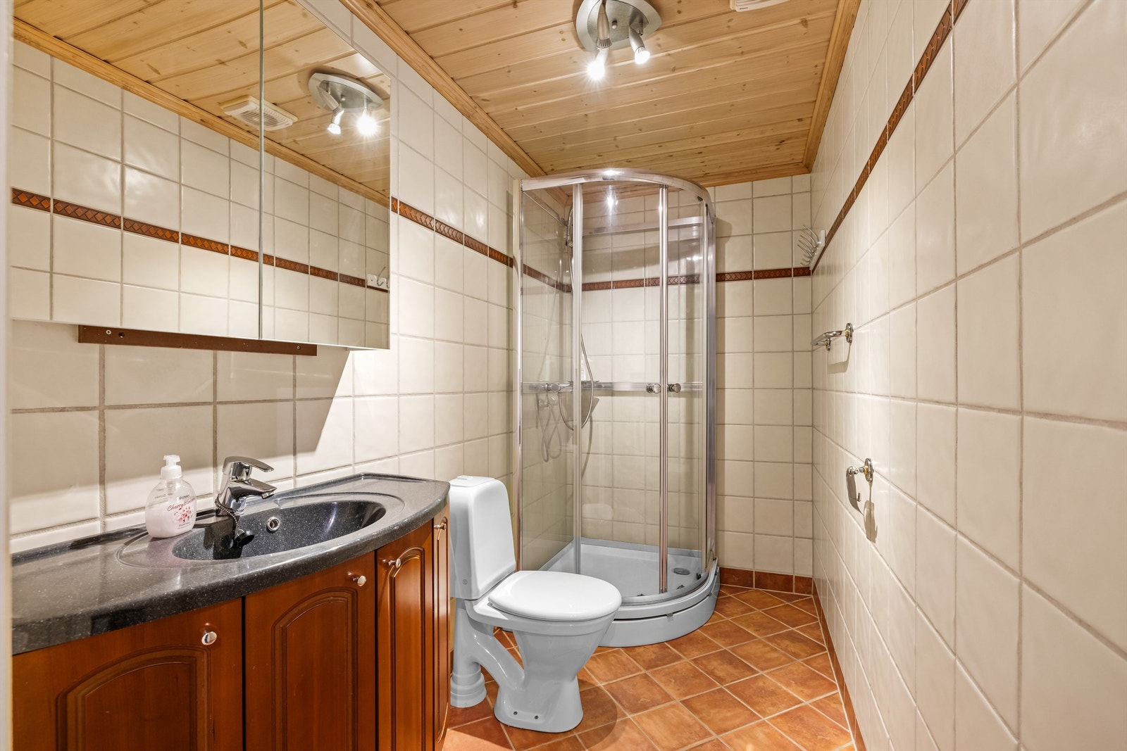 Badet i første etasje har flislagt gulv med gulvvarme, dusjkabinett og speilskap. Galleribilde