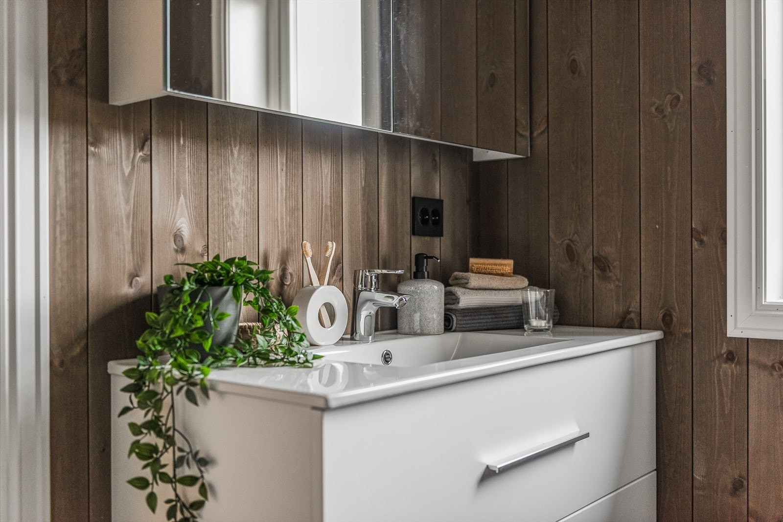 Lys baderomsinnredning med store skuffer og heldekkende servantplate, samt speilskap med tilhørende belysning. Galleribilde