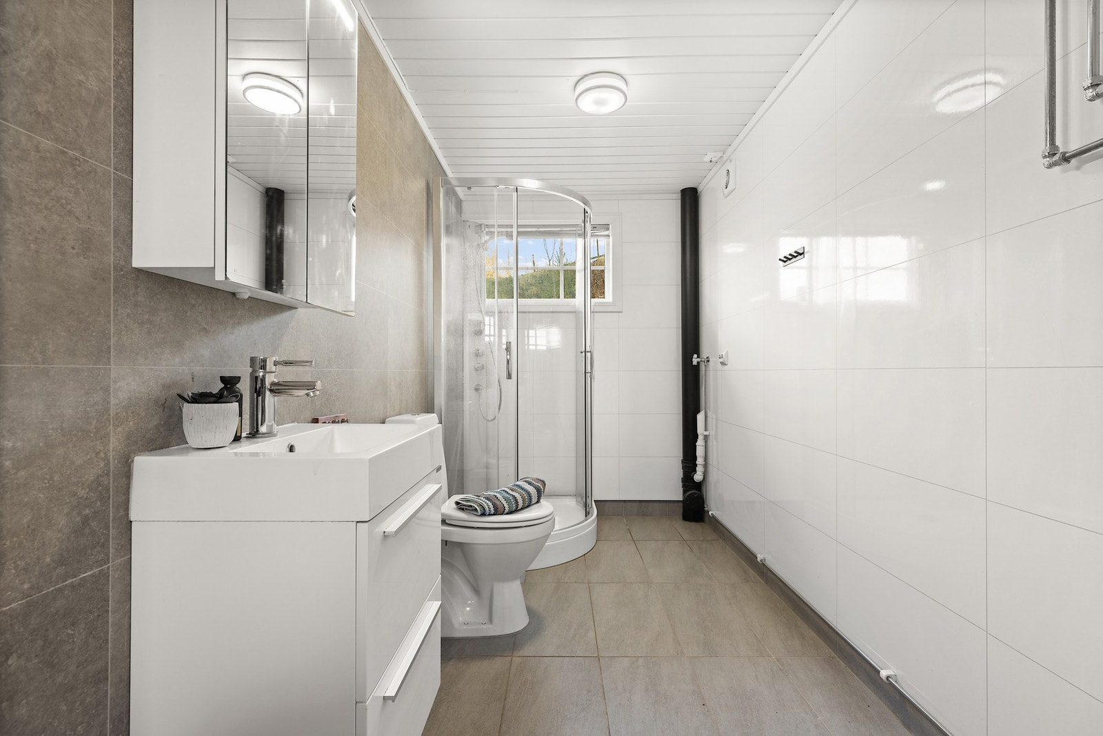 Garasjen har eget bad med varmtvannstank, dusjkabinett, toalett og servant med speilskap. Galleribilde