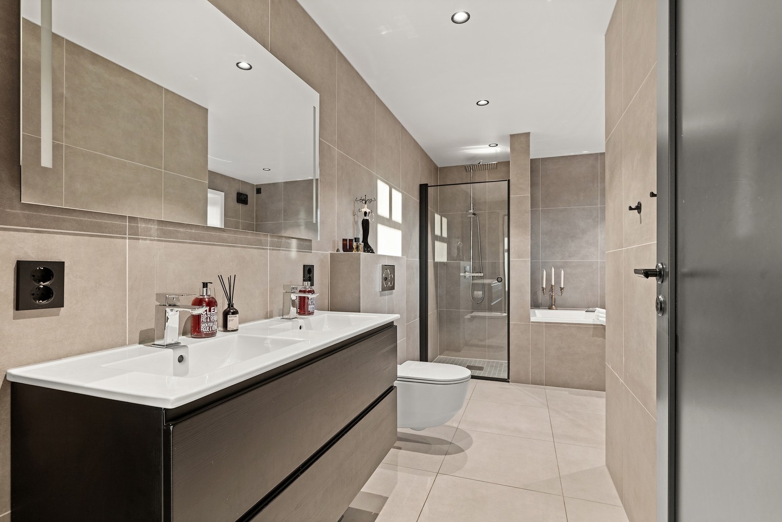 Bad i 1. etg fra 2025 er smakfullt innredet med 2 nedfelte servanter med skuffeseksjoner, toalett og innfliset badekar. Galleribilde