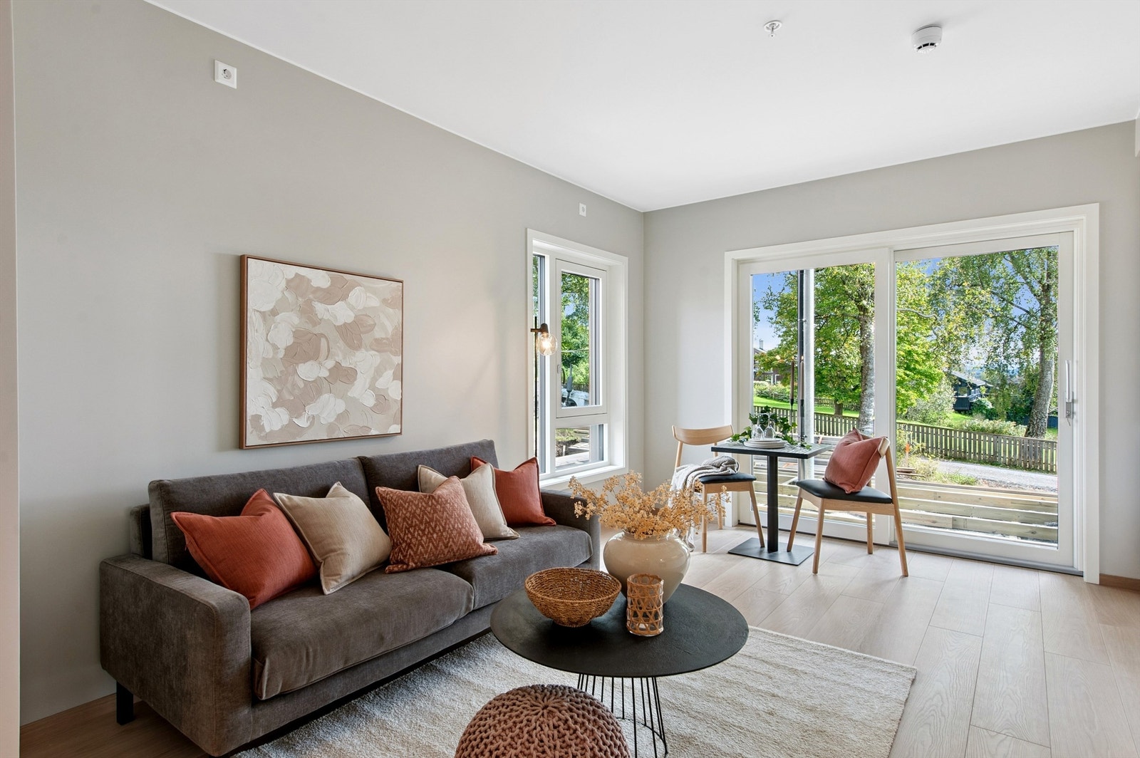 Snerten leilighet med lyst allrom med plass til sofa og liten spiseplass. Den flotte uteplassen er nå ferdigstilt. Plen vil bli tilsådd våren 2026. Galleribilde