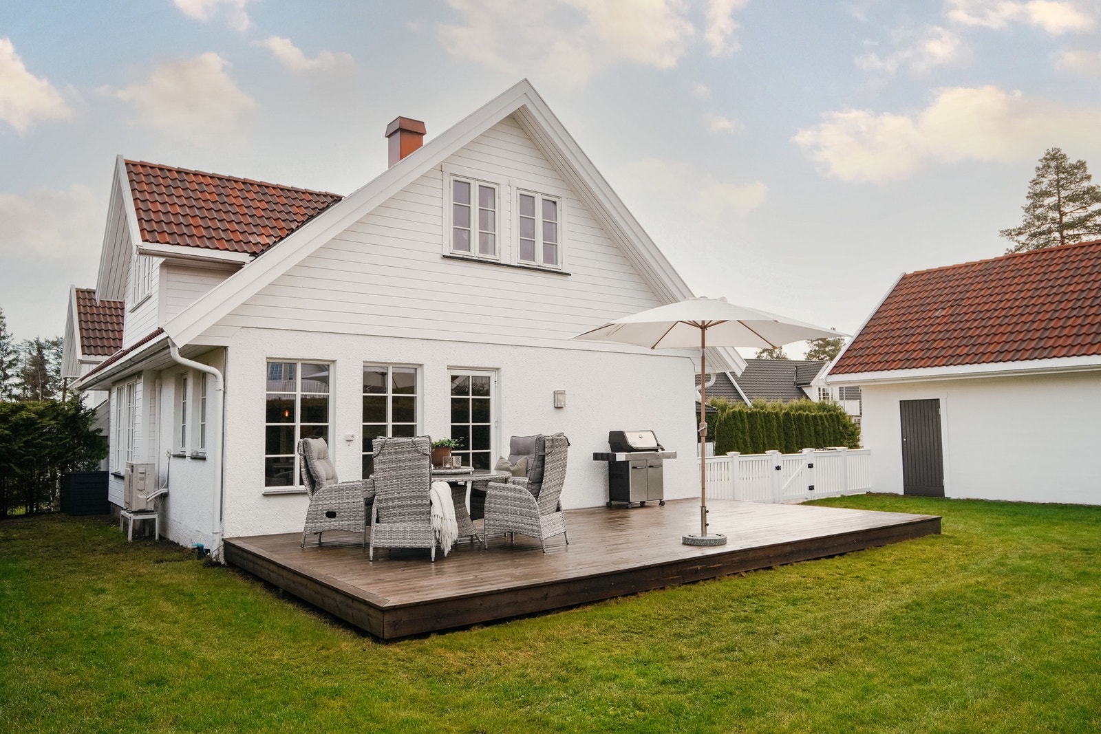 Videre er tomten pent opparbeidet med gressplen og hekk Galleribilde