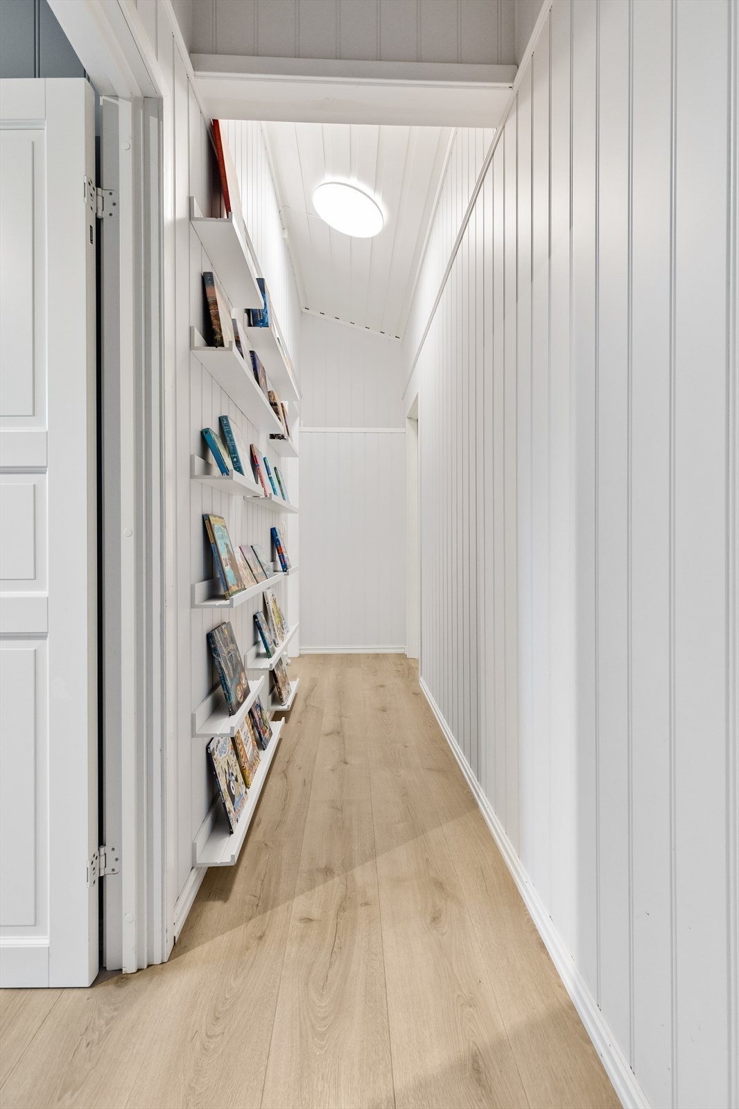 Gangen er smart utnyttet med plassbygde hyller for bøker eller dekor. Galleribilde