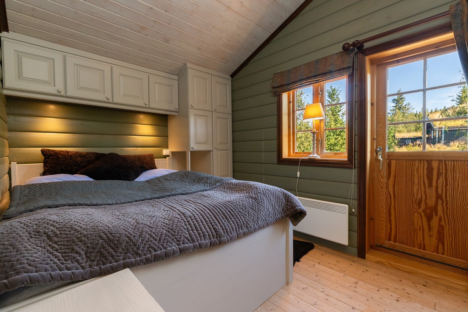 Soverom 2 har dobbeltseng, med skuffe i sokkel, inntil vegg, med stedbygde skap over og ved siden Galleribilde